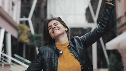 Happy young woman walking on the street and moving in dance. Slow motion photo