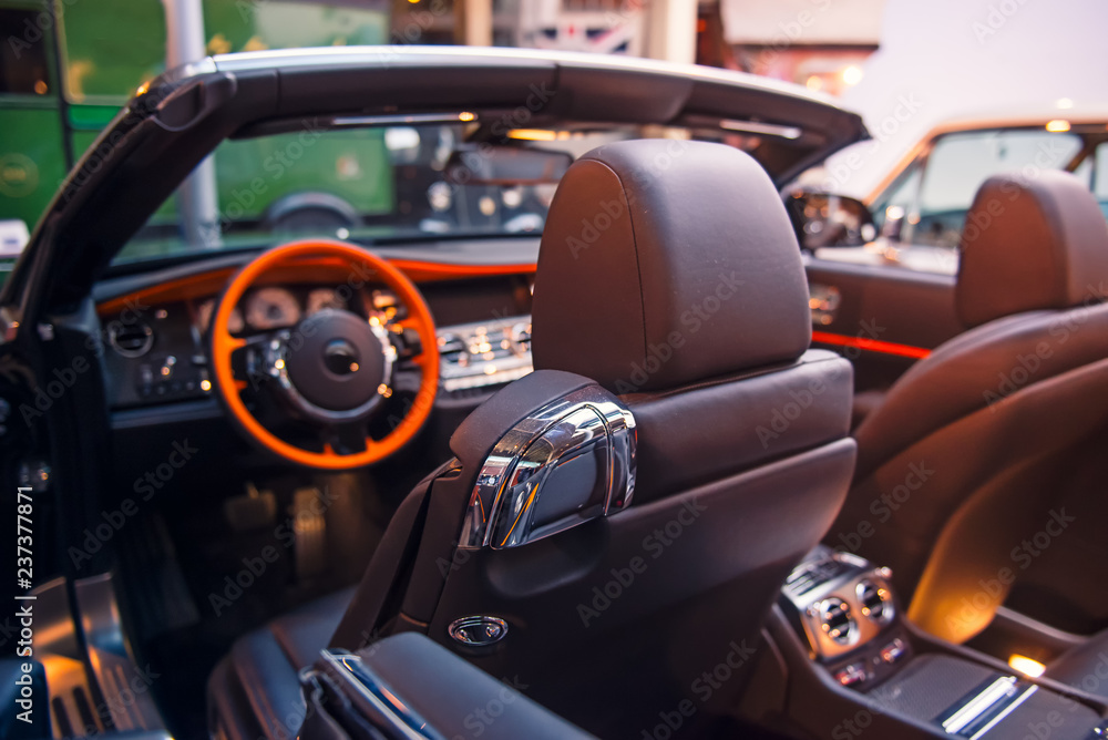 Luxury convertible car interior. Steering wheel, shift lever and dashboard. Driver side view. Selective focus, copy space.