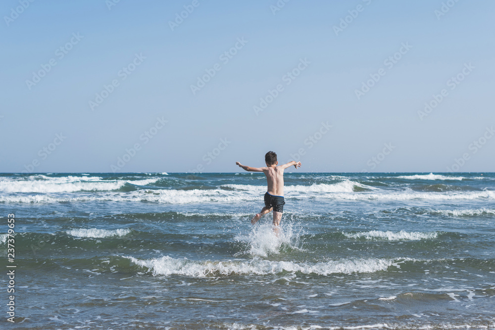 Boy Jumping In Sea Waves with Water Splashes. Concept of summer vacation Boy Jumping In Sea Waves with Water Splashes. Concept of summer vacation
