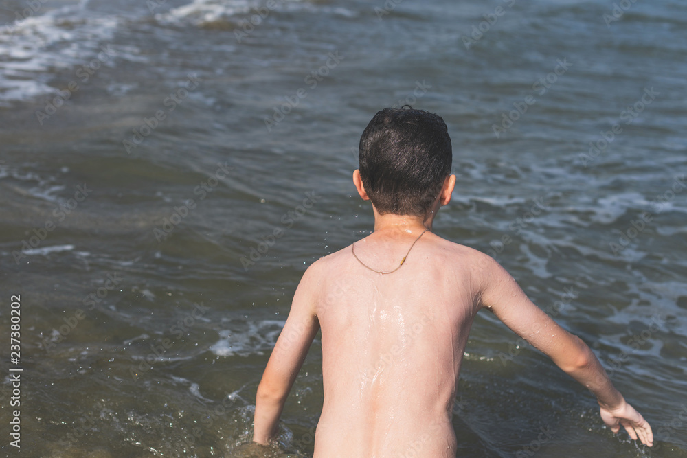 Fototapeta premium Teen boy after dives in the wave of sea in the tropical resorts. Concept of summer vacation