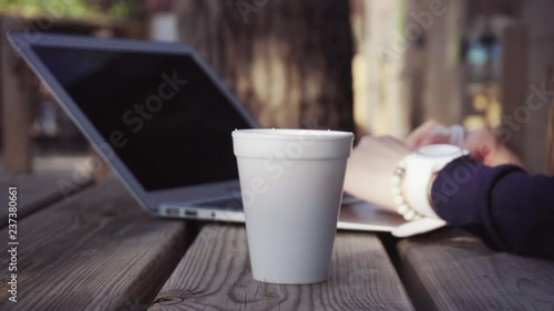 Woman typing on a laptop and drinking coffee outdoors. Teleworking, communication on the Internet or education by camping Marghera, Venice, Italy