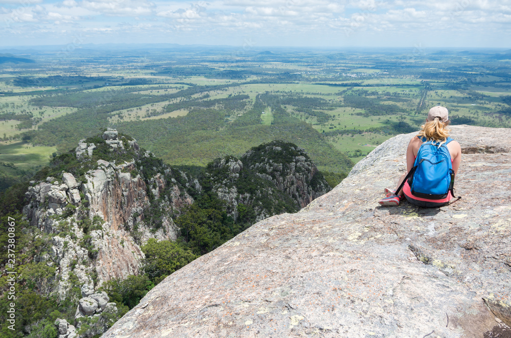 Young beautiful woman looking out over the Australian landscape from the top of a mountain
