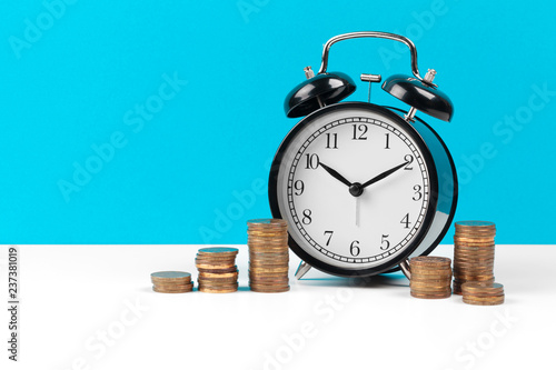 Alarm clock and money coins on the table.