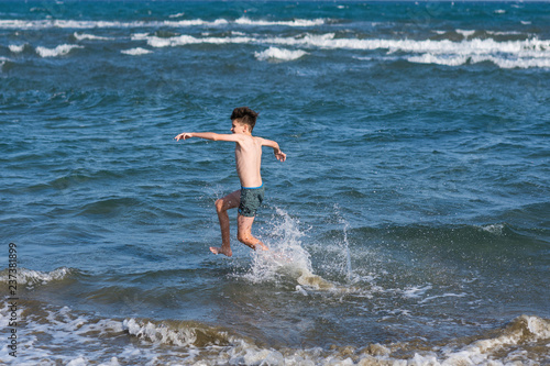 Boy Jumping In Sea Waves with Water Splashes. Concept of summer vacation