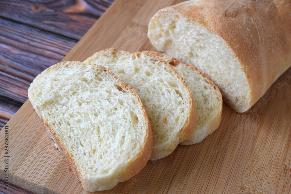 Fresh homemade bread sliced on wooden background.