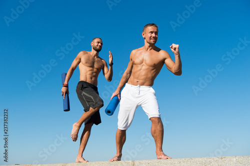 Fototapeta Naklejka Na Ścianę i Meble -  Towards health. Men hurry up outdoor yoga practice. Muscular men training on fresh air. Developing muscular strength in health club. Sport and health care. Daily exercises to maintain health