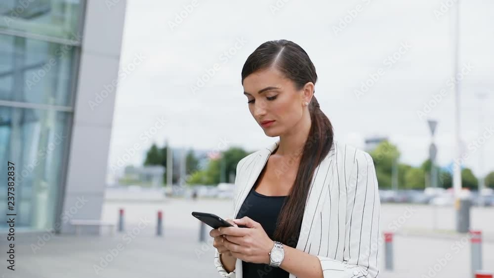 Beautiful Business Woman Using Phone While Walking Near Office Beautiful Business Woman Using Phone While Walking Near Office