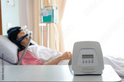 Obstructive sleep apnea therapy..Cpap machine is treating senior patient woman wearing Cpap mask sleeping smoothly without snoring in hospital room..