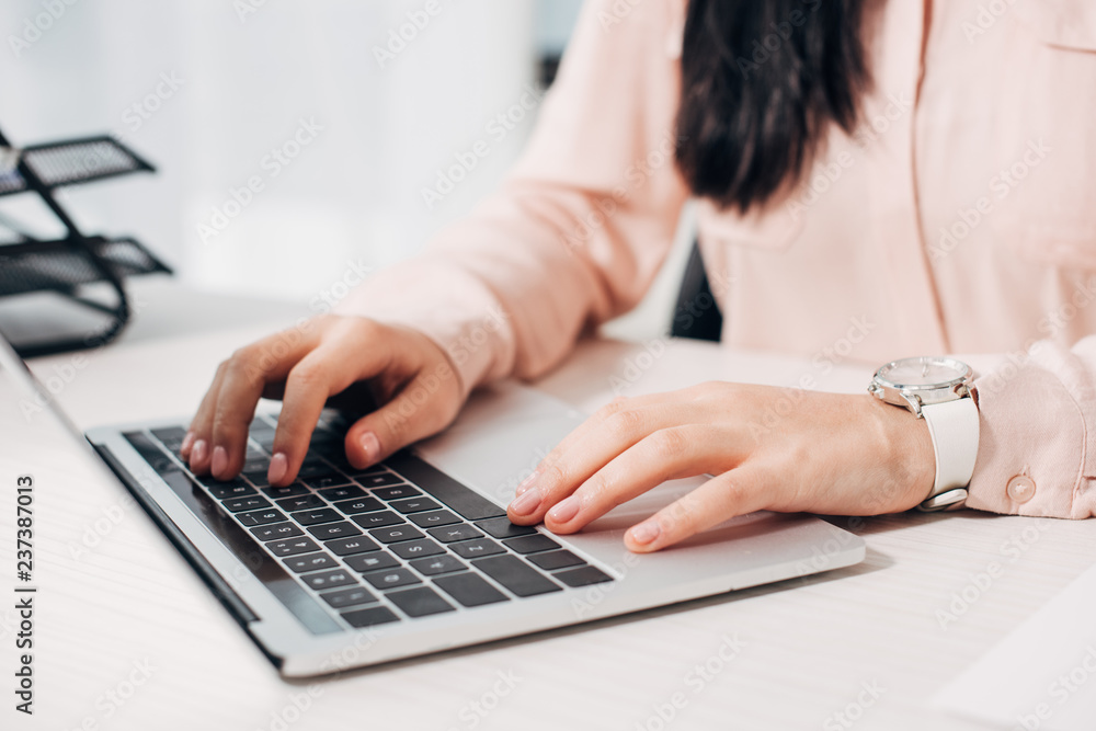 Cropped view of businesswoman typing on computer keyboard in office