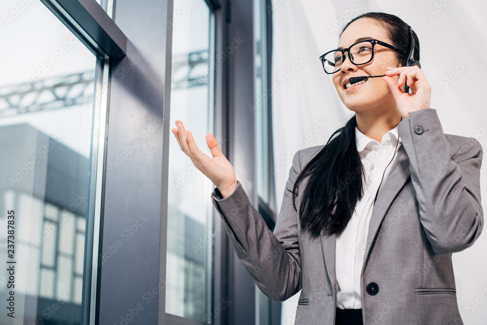 attractive call center operator standing by window and speaking in microphone in office attractive call center operator standing by window and speaking in microphone in office