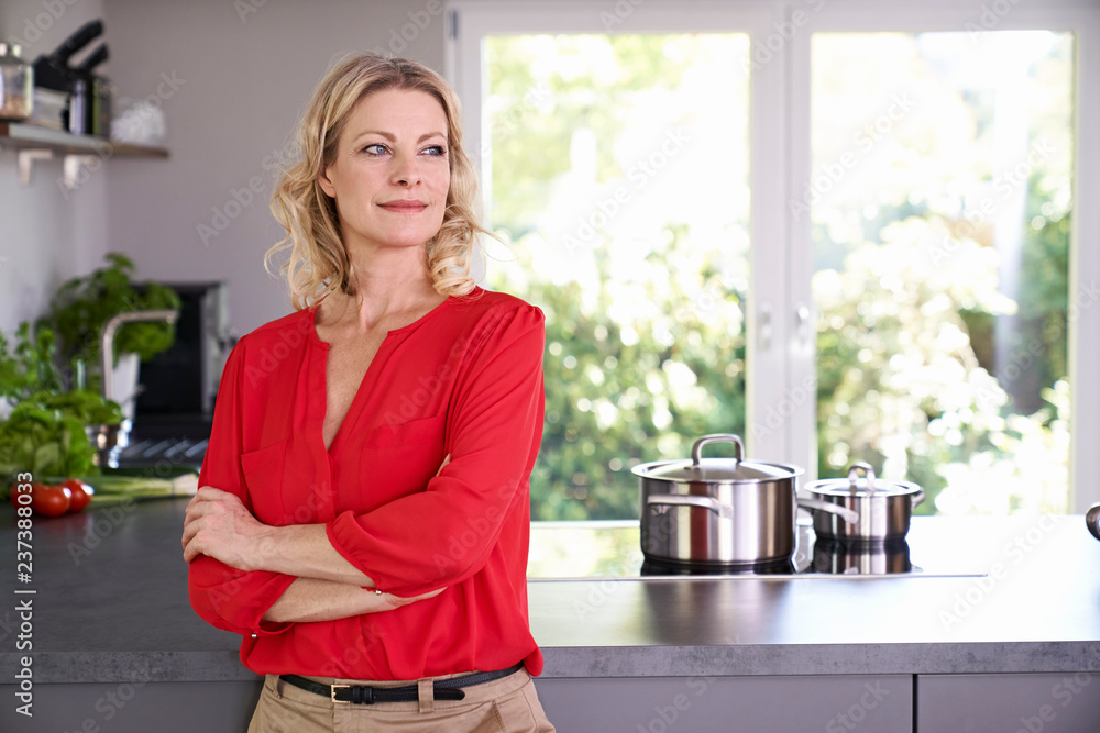 Confident woman wearing red blouse standing in kitchen Confident woman wearing red blouse standing in kitchen