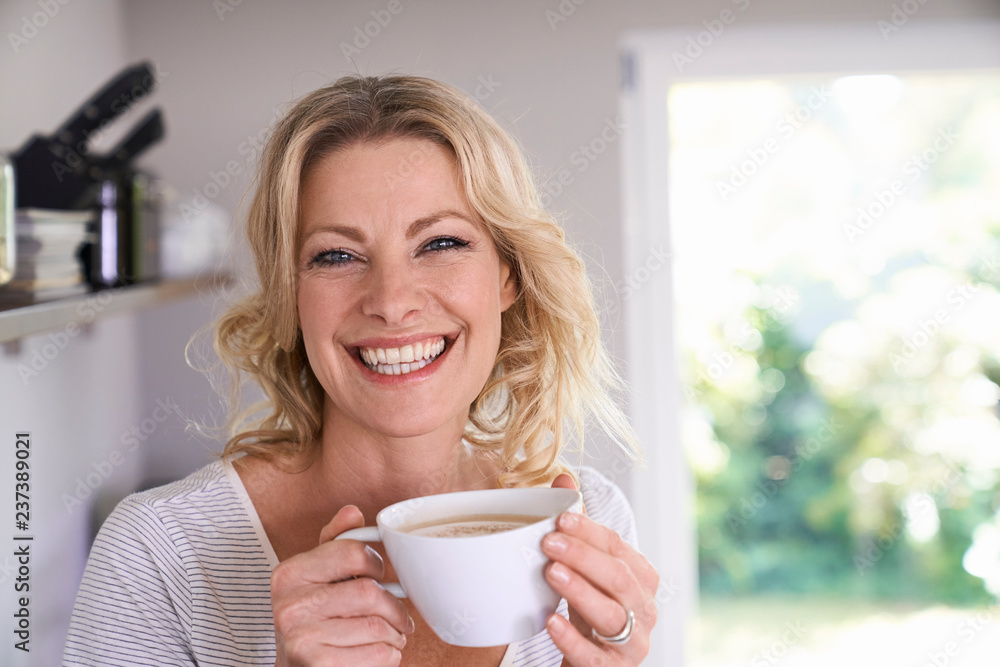 Portrait of smiling woman drinking coffee in kitchen Portrait of smiling woman drinking coffee in kitchen