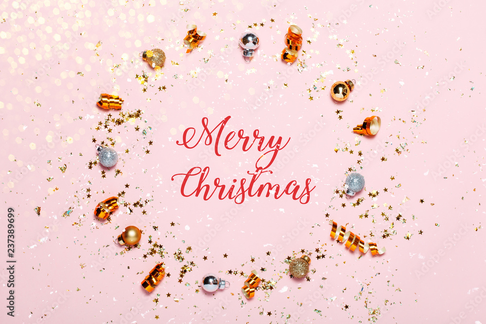 Christmas background with golden decorations put as frame on pink pink background. Bright and festive flat lay. Top view, Merry Christmas text. Greetings for christmas or new year.