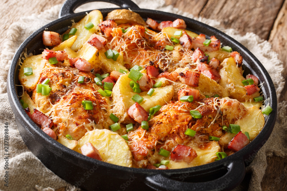 spicy chicken breast with potatoes, bacon and cheese close-up in a frying pan. horizontal