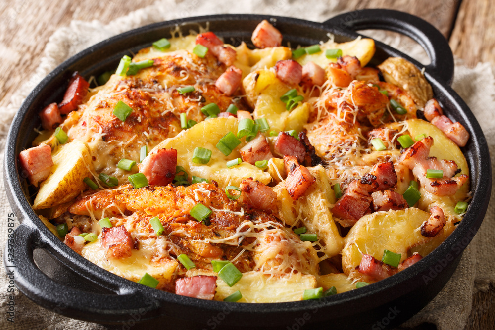 Delicious homemade baked chicken fillet with potatoes, bacon and cheese close-up in a frying pan. horizontal Delicious homemade baked chicken fillet with potatoes, bacon and cheese close-up in a frying pan. horizontal