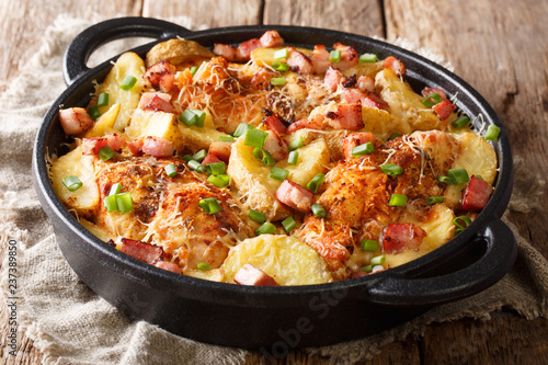 Traditional chicken breast baked with potatoes, bacon and cheese close-up in a frying pan. horizontal