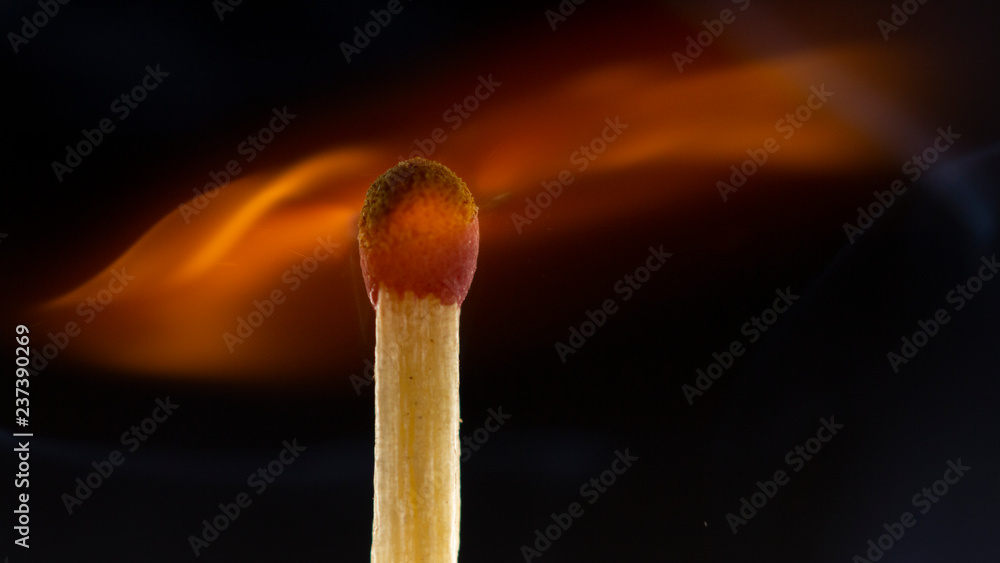 Burning wooden match with a red match head on a black background. Burning wooden match with a red match head on a black background.