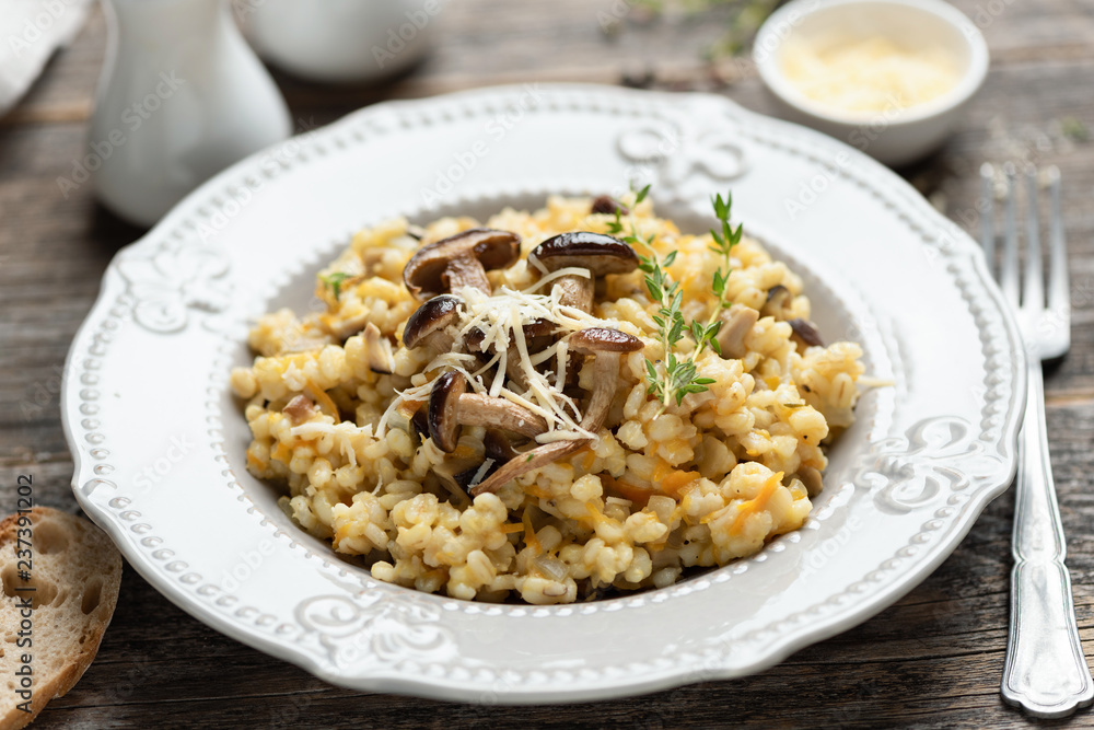 Pearl barley mushroom risotto on wooden table, closeup view, selective focus