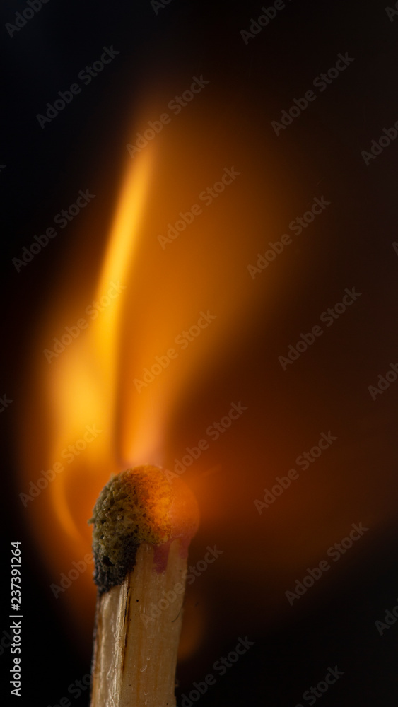 Burning wooden match with a red match head on a black background. Burning wooden match with a red match head on a black background.