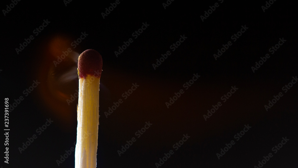 Burning wooden match with a red match head on a black background. Burning wooden match with a red match head on a black background.