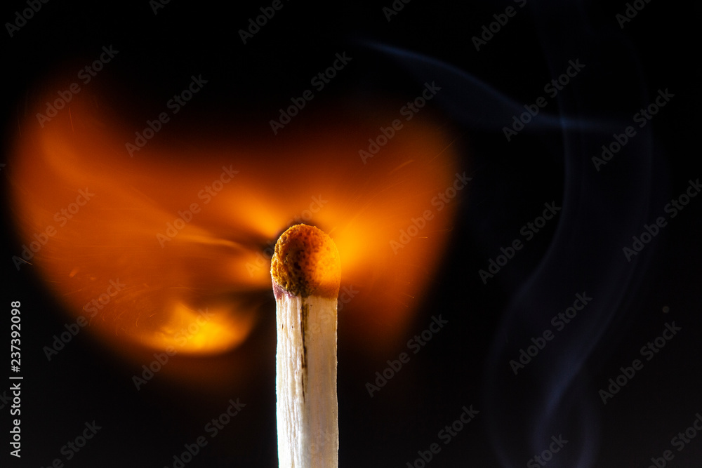 Burning wooden match with a red match head on a black background. Burning wooden match with a red match head on a black background.