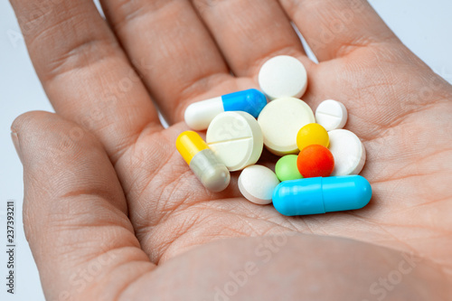 Many color pills and capsules in hand. closeup