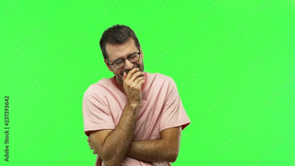 man smiling a lot while covering mouth on green screen chroma key background man smiling a lot while covering mouth on green screen chroma key background