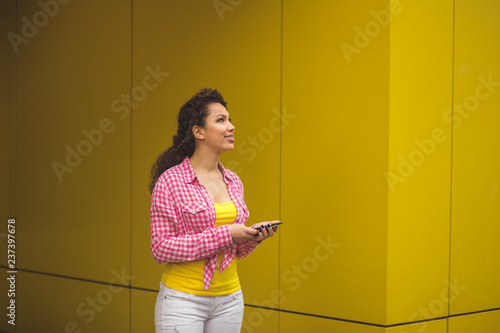 Portrait of cool cheerful girl having video-call with lover holding smart phone in hand shooting selfie on front camera isolated on yellow background enjoying weekend.