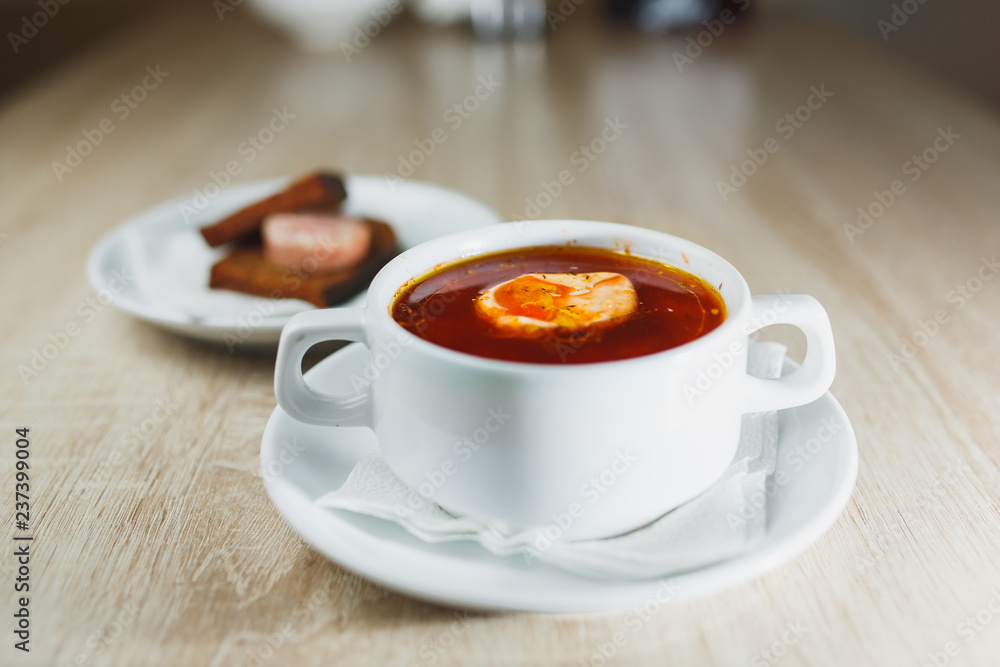 Ukrainian traditional borsch. Russian vegetarian red soup in white bowl on red wooden background. Top view. Borscht, borshch with beet Ukrainian traditional borsch. Russian vegetarian red soup in white bowl on red wooden background. Top view. Borscht, borshch with beet