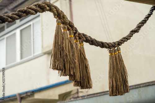 Closeup detail of a Shimenawa rope hanging from a Torii gate during a rainy day in Takachiho. Miyazaki, Japan. Travel and culture. photo