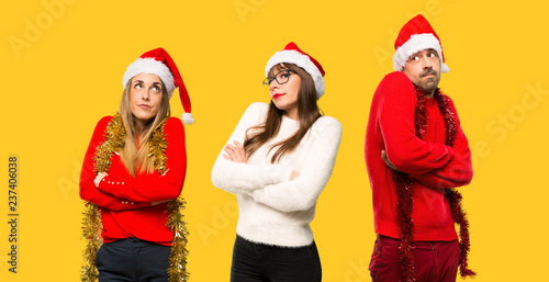 A group of people Blonde woman dressed up for christmas holidays making unimportant gesture while lifting the shoulders on yellow background