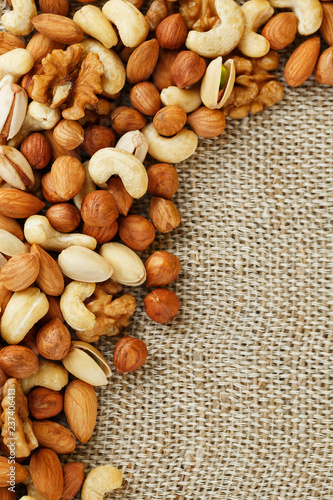 Mix of nuts lying on a background of brown cloth burlap.