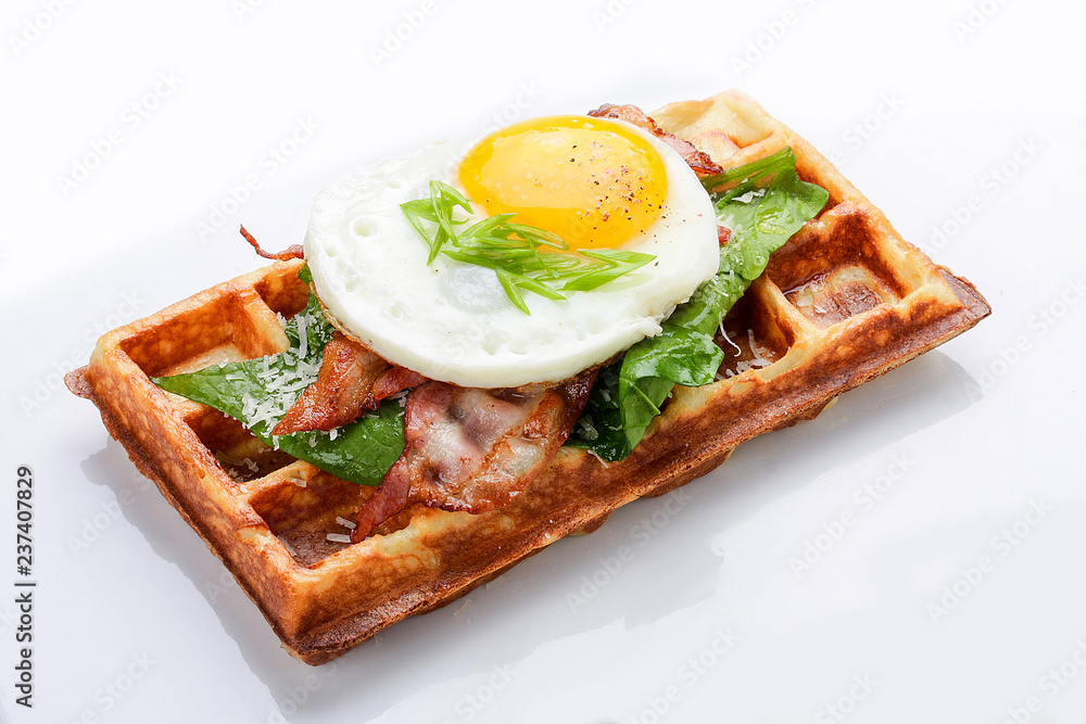 Belgian waffle on a white background. Stuffed with bacon, eggs and salad.