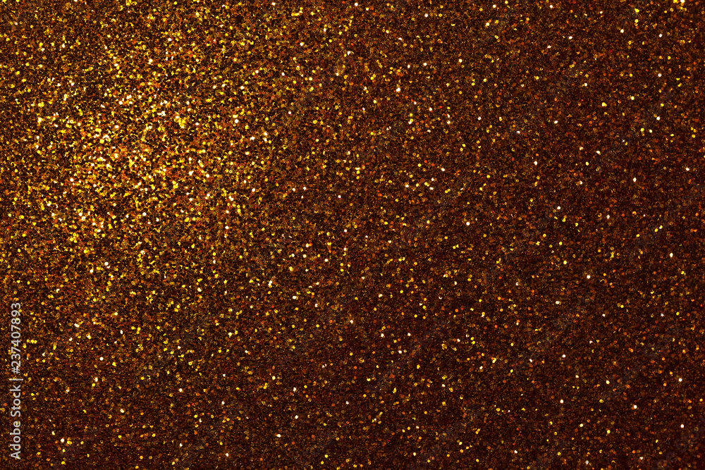 Dark golden sparkling background from small sequins, closeup. Brilliant backdrop.