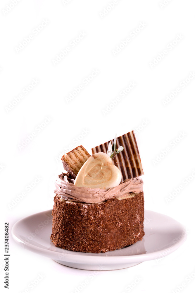 A biscuit cake is sprinkled with cocoa with chocolate cream, a heart of white chocolate, a slice of chocolate tile and a delicious waffle isolated A biscuit cake is sprinkled with cocoa with chocolate cream, a heart of white chocolate, a slice of chocolate tile and a delicious waffle isolated