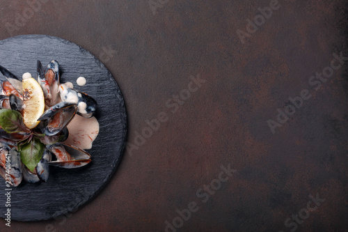 Fototapeta Naklejka Na Ścianę i Meble -  Seafood mussels in cream sauce with lemon and basil on a stone and rusty background