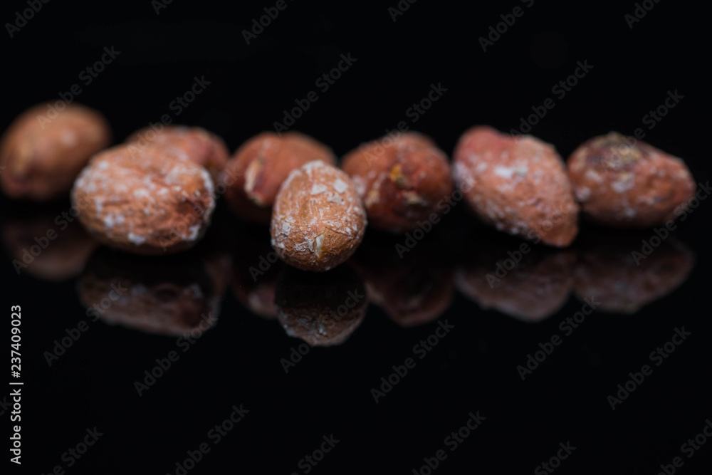 Fototapeta premium Salted roasted peanuts close up macro shot on shiny black surface, space for text.