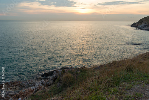 Wide view of a sunset from the peak of Khao Laem Ya overlooking the calm blue sea on a cloudy day. Rayong, Thailand. Travel and nature.