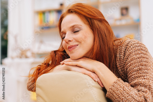 Blissful young redhead woman sitting daydreaming photo