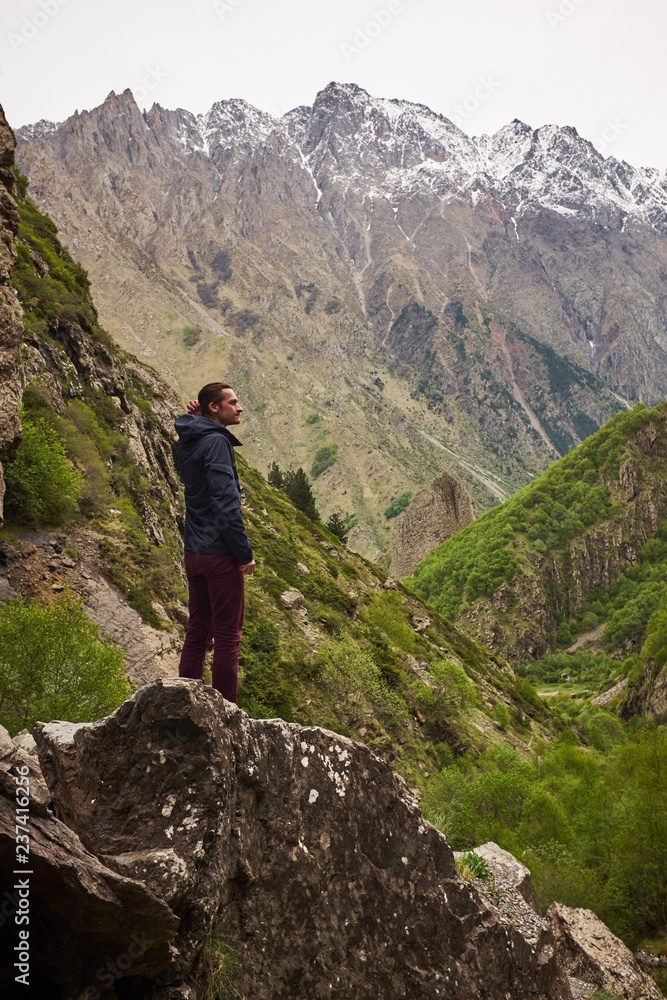 Man alone with nature, stands on dangerous cliff or rock formation overlooking epic beautiful mountain valley, path leads to edge, inspiring wanderlust outdoor hiking lifestyle