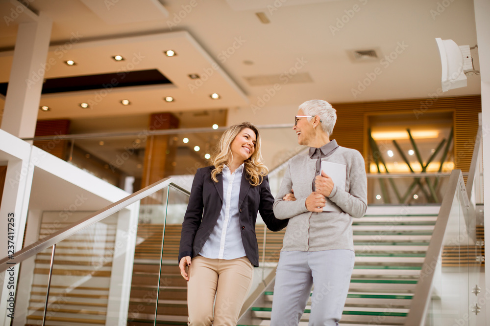 Senior and young businesswomen getting down the stairs Senior and young businesswomen getting down the stairs
