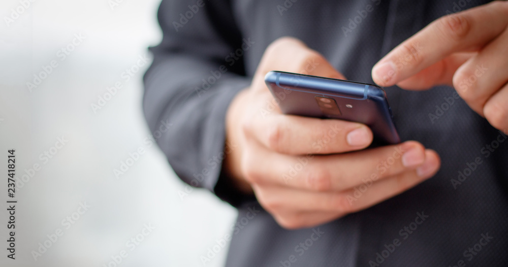 Man using mobile smartphone - focus on top of the phone Man using mobile smartphone - focus on top of the phone