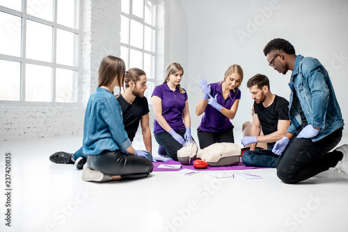 Group of young people learning to make artificial breathing with medical dummies during the first aid training in the white room
