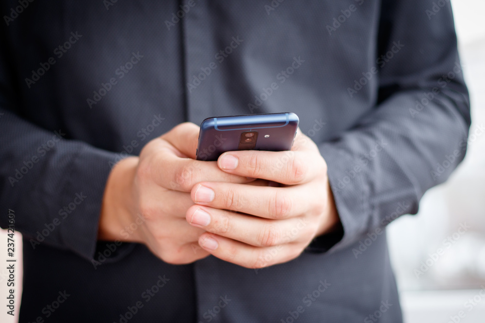 Male hand holding a cell smartphone and writing sms Male hand holding a cell smartphone and writing sms