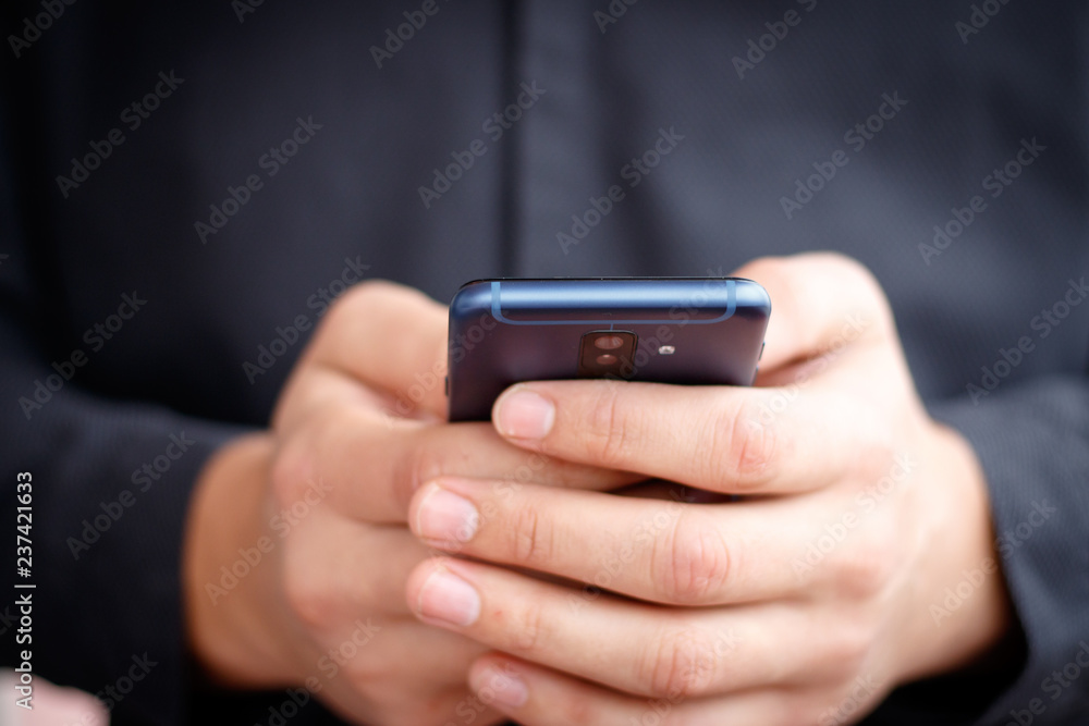 Male hand holding a cell smartphone and writing sms Male hand holding a cell smartphone and writing sms
