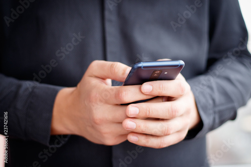 Male hand holding a cell smartphone and writing sms