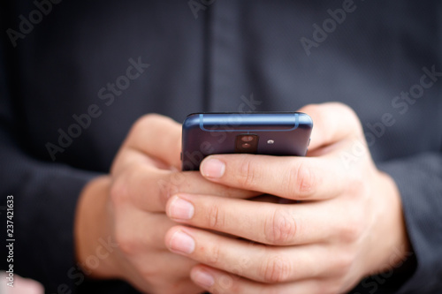 Male hand holding a cell smartphone and writing sms