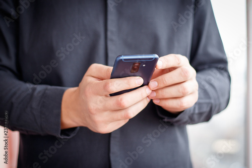 Male hand holding a cell smartphone and writing sms