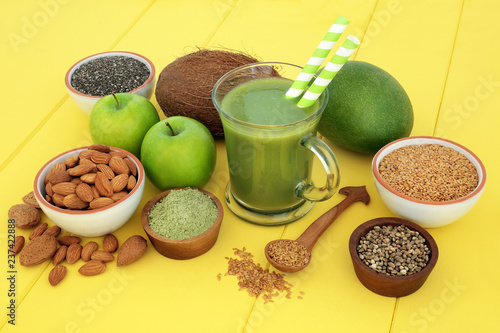 Fresh fruit juice health drink with matcha  flax  chia and hemp seed  nuts and fruits on yellow wood background. High in omega 3  antioxidants  vitamins and dietary fibre.