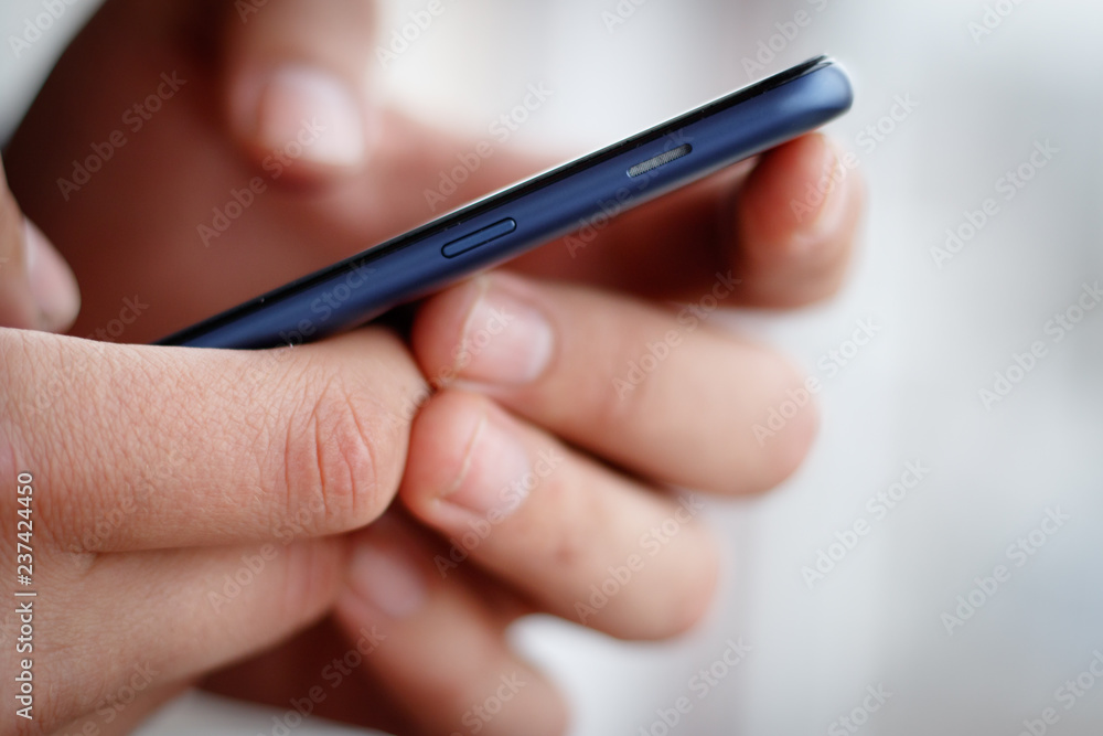 Male hand holding a cell phone and writing sms Male hand holding a cell phone and writing sms